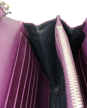 Close-up of a purple pebbled leather wallet or card holder showing the interior, multiple vertical card slots, a black lining, and a silver zipper.
