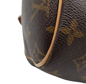 Close-up of a Louis Vuitton monogram canvas bag corner showing the classic brown and tan pattern with tan leather piping on a white background.