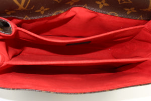 Close-up of the interior of a Louis Vuitton handbag, showing a bright red fabric lining with the classic brown monogram canvas visible along the top edge.