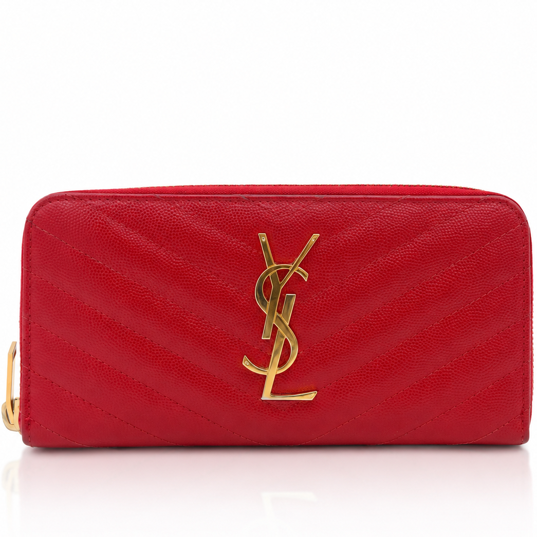 A red Saint Laurent zip-around wallet in textured caviar leather with a gold-tone YSL logo on the front, set against a plain white background.