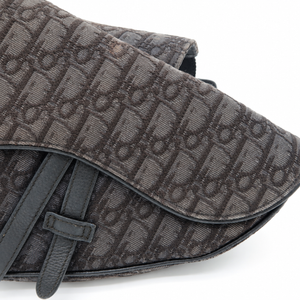 Close-up of a dark brown Dior Oblique coated canvas bag with a dark brown leather strap and trim, set against a plain white background.