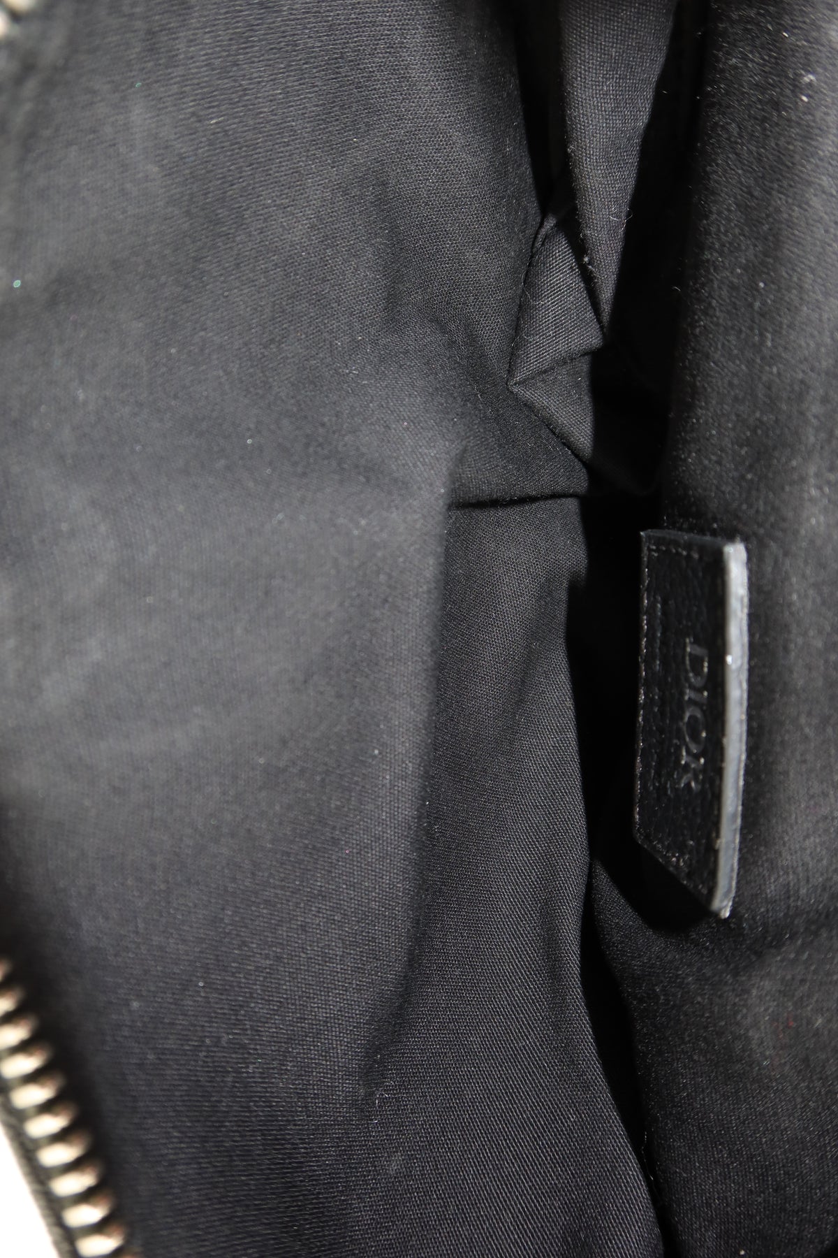 Close-up of a black fabric item with a small black leather tag embossed with the brand name Dior.