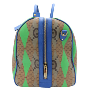 A Gucci backpack in brown GG Supreme monogram canvas with bright green and blue argyle diamond patterns, featuring blue leather trim and handles, and gold-tone hardware.