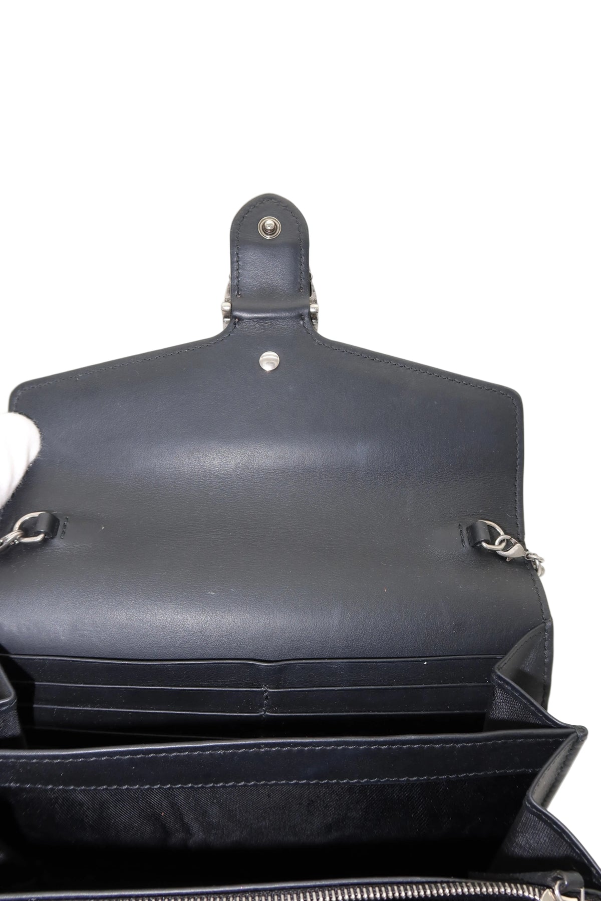 Close-up of the interior of a black leather clutch or wallet, showing the inside flap, card slots, and zipper compartment against a plain white background.