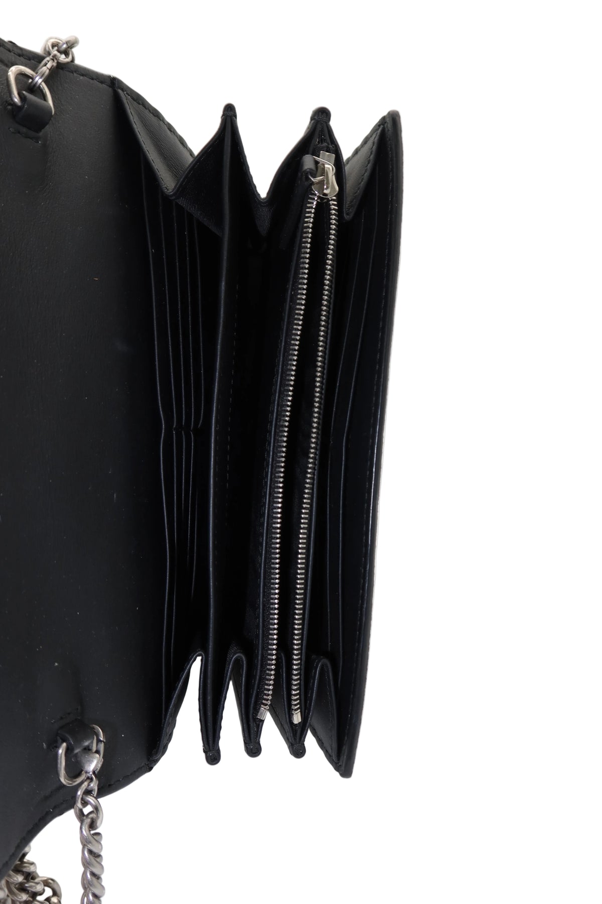 A close-up of a black multi-compartment wallet or clutch shown open, displaying its interior card slots, zippered pocket, and silver-tone chain strap on a white background.