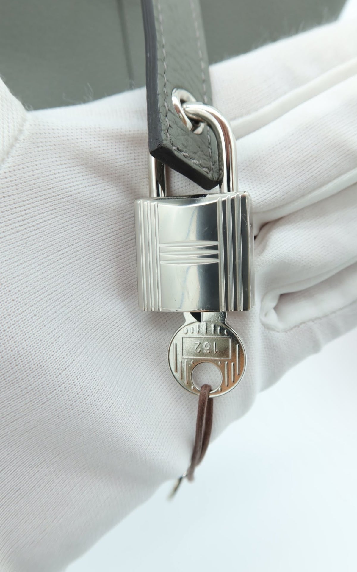 Hermès Taurillon Clemence Picotin Lock 18 PM Etain – Good Condition – a close-up of a silver padlock with a key attached,